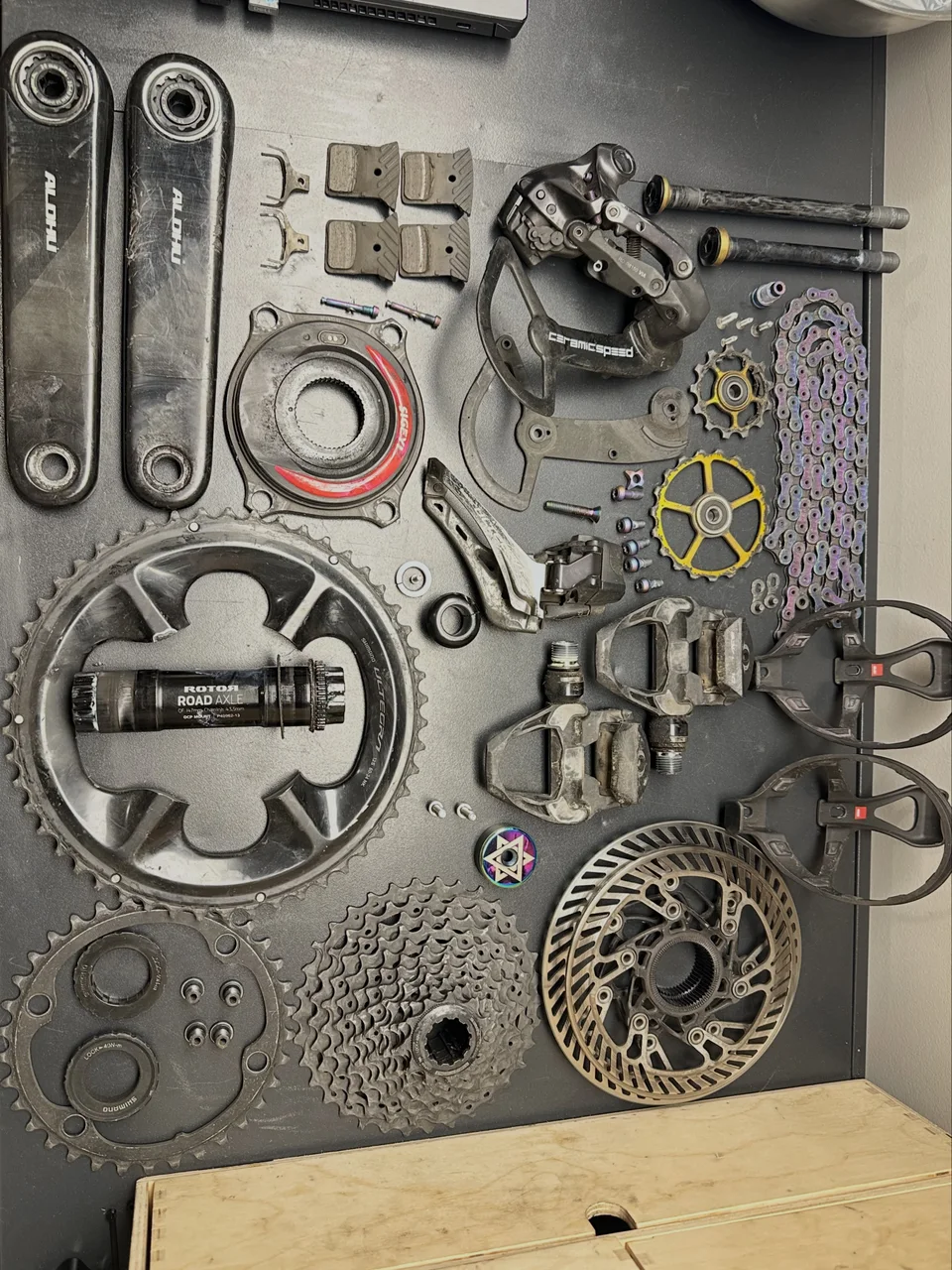 Cranks, chainrings, cassette, brakes and bearings laid out on a workshop bench